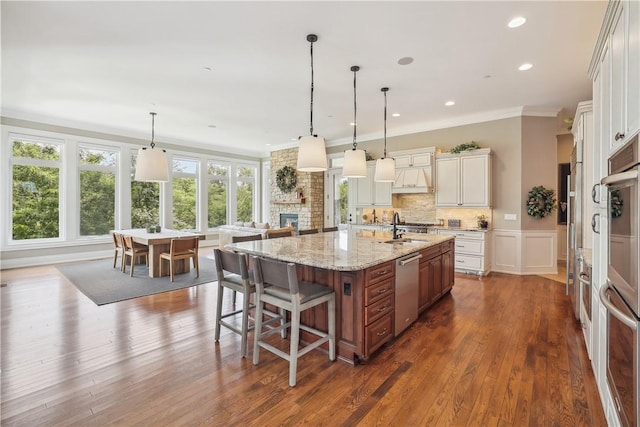 4701 150th St, Urbandale, IA 50323 - kitchen featuring stainless steel appliances, crown molding, a large island with sink, dark wood-style flooring, and a kitchen bar