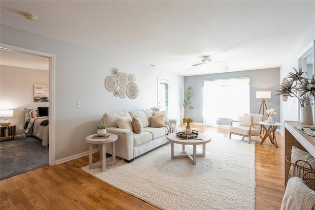 living area featuring baseboards, a textured ceiling, and wood finished floors