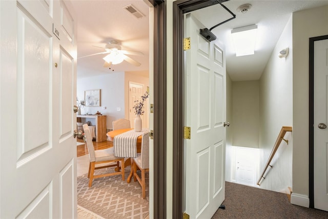 hallway featuring light colored carpet, an upstairs landing, and visible vents