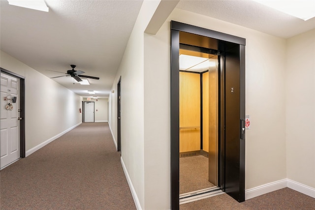 hallway featuring elevator, baseboards, and carpet floors