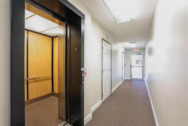 hallway with elevator, visible vents, baseboards, and carpet floors