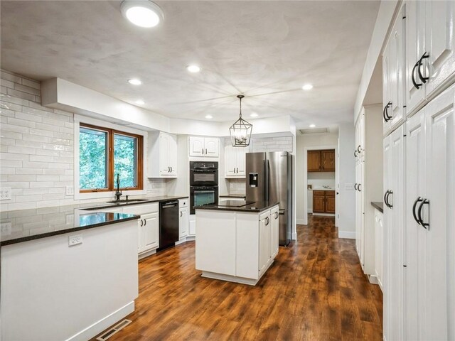 kitchen with hanging light fixtures, black appliances, white cabinets, and dark hardwood / wood-style floors