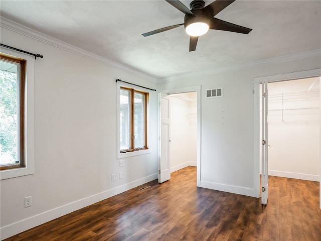 unfurnished bedroom featuring dark hardwood / wood-style flooring, multiple windows, and a spacious closet