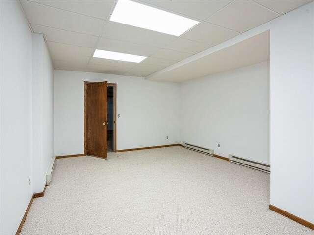 spare room featuring light carpet, baseboard heating, and a paneled ceiling