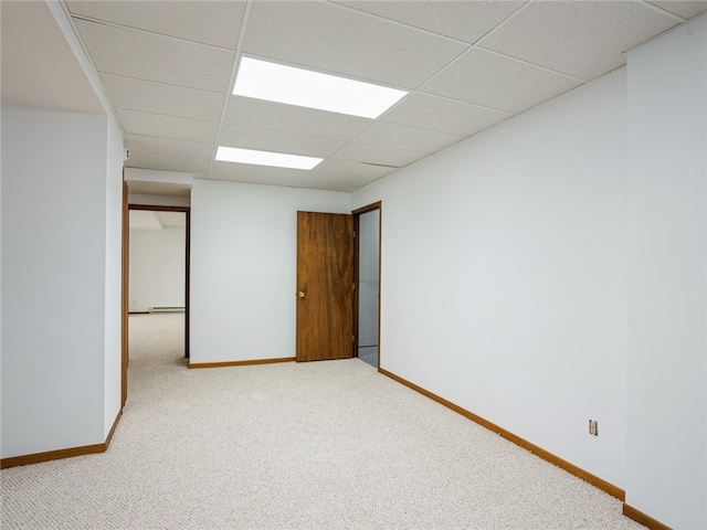 empty room with a drop ceiling, carpet, and baseboard heating