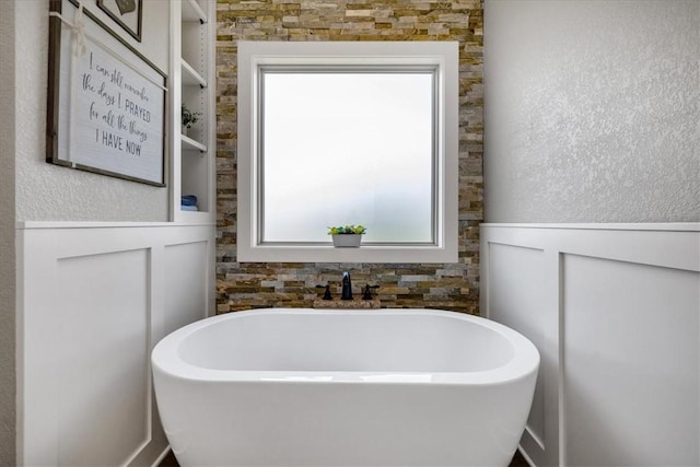 bathroom with a wealth of natural light, built in features, and a bathtub