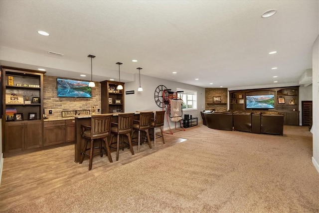 bar featuring light colored carpet, hanging light fixtures, and a textured ceiling