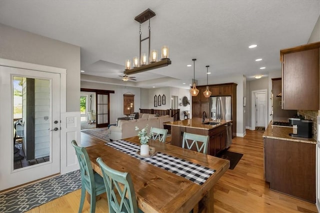 dining room featuring light hardwood / wood-style floors, sink, ceiling fan, and a textured ceiling