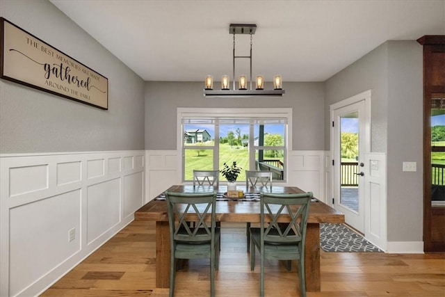 dining area with light wood-type flooring and a notable chandelier