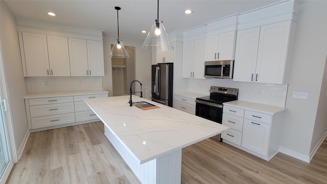 kitchen featuring appliances with stainless steel finishes, white cabinetry, a kitchen island with sink, and sink