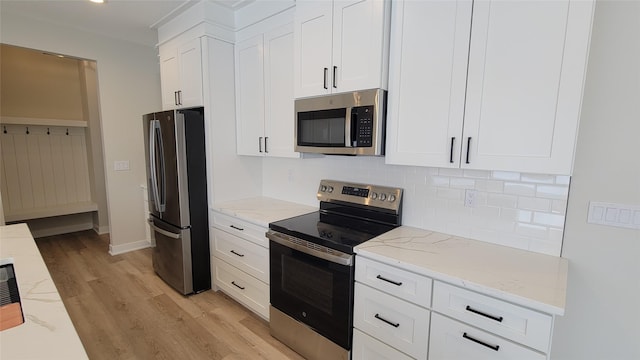 kitchen with white cabinetry, stainless steel appliances, tasteful backsplash, light stone counters, and light hardwood / wood-style flooring