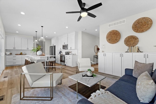 living room featuring ceiling fan and light hardwood / wood-style flooring