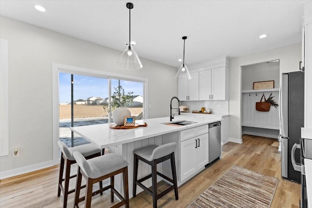 kitchen with white cabinetry, stainless steel appliances, sink, and a kitchen island with sink