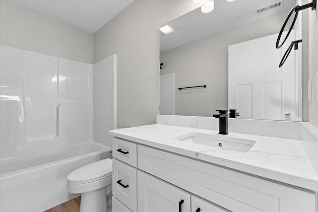 full bathroom with vanity, hardwood / wood-style floors, washtub / shower combination, and toilet