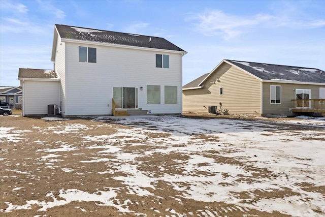 snow covered back of property featuring central AC