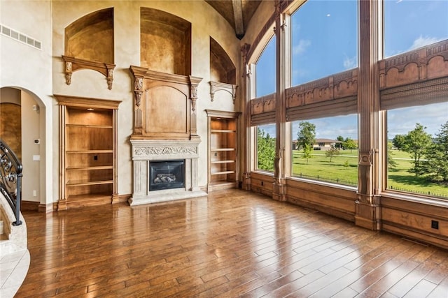 unfurnished living room featuring a high ceiling, built in features, and dark hardwood / wood-style flooring