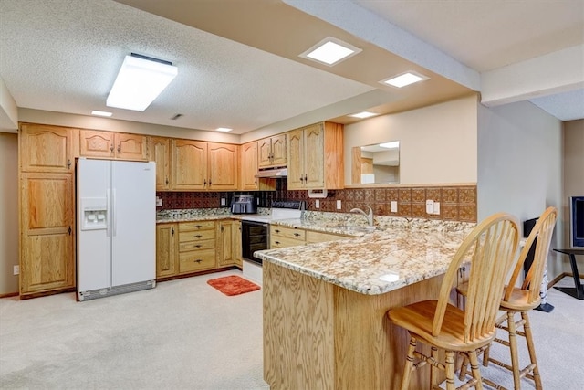 kitchen featuring a textured ceiling, a kitchen breakfast bar, white appliances, kitchen peninsula, and light colored carpet