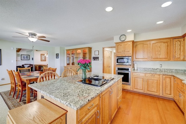 kitchen with a center island, ceiling fan, stainless steel appliances, and light hardwood / wood-style floors