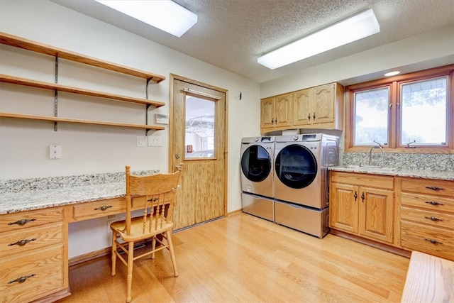 washroom with light wood-type flooring, sink, separate washer and dryer, cabinets, and a textured ceiling