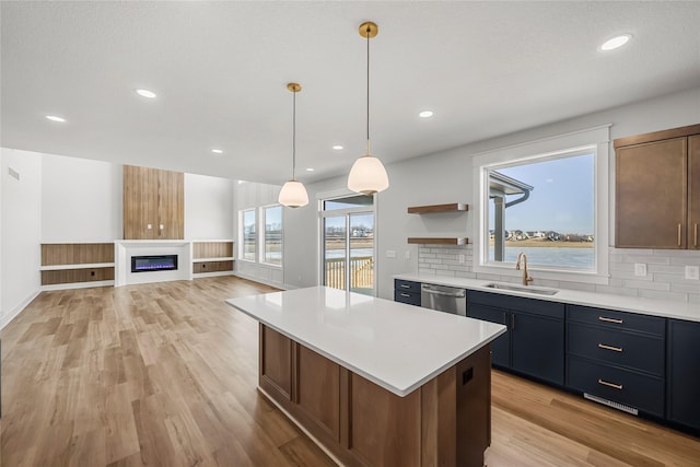 kitchen featuring dishwasher, sink, a water view, a kitchen island, and decorative backsplash