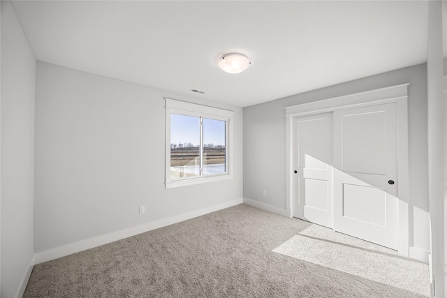 unfurnished bedroom with a closet and light carpet