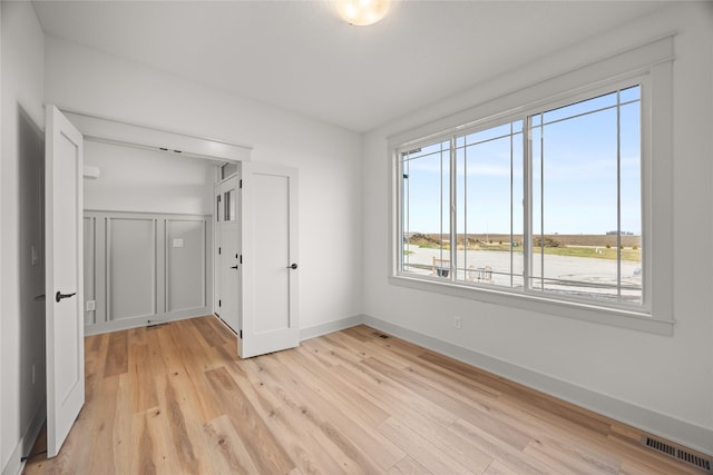 unfurnished room featuring light wood-type flooring and a water view