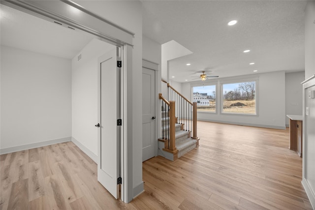 corridor featuring a textured ceiling and light hardwood / wood-style flooring