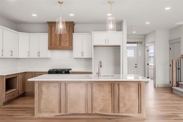 kitchen with a center island with sink, light wood-type flooring, white cabinetry, and sink