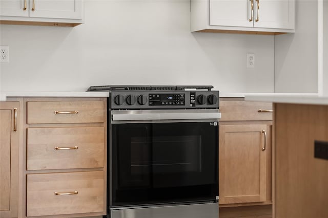 kitchen featuring light brown cabinetry and stainless steel range oven