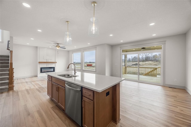 kitchen with dishwasher, sink, decorative light fixtures, and an island with sink