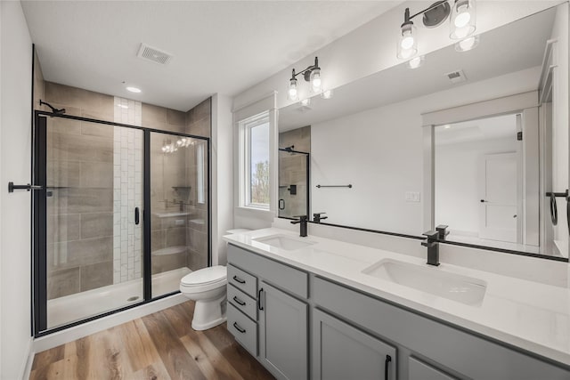 bathroom with hardwood / wood-style floors, vanity, toilet, and an enclosed shower