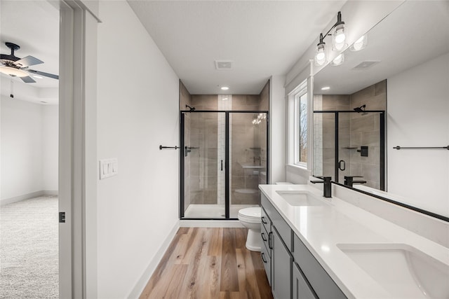 bathroom featuring hardwood / wood-style floors, vanity, toilet, and walk in shower