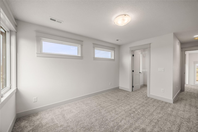 unfurnished bedroom with light carpet, a textured ceiling, and a closet