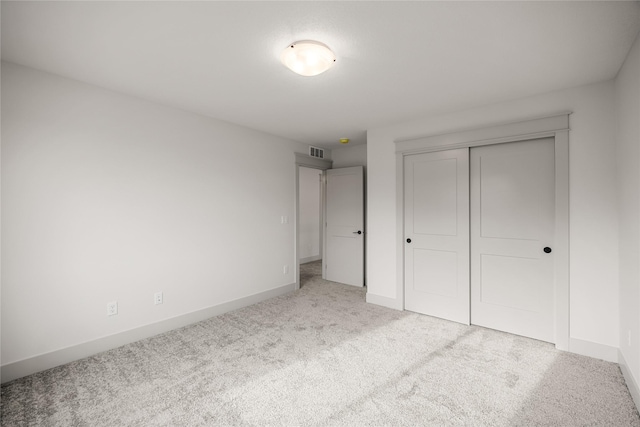 unfurnished bedroom with a closet and light colored carpet