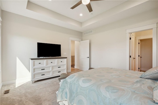 carpeted bedroom with a raised ceiling and ceiling fan