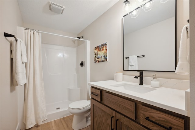 bathroom featuring hardwood / wood-style flooring, vanity, toilet, and curtained shower