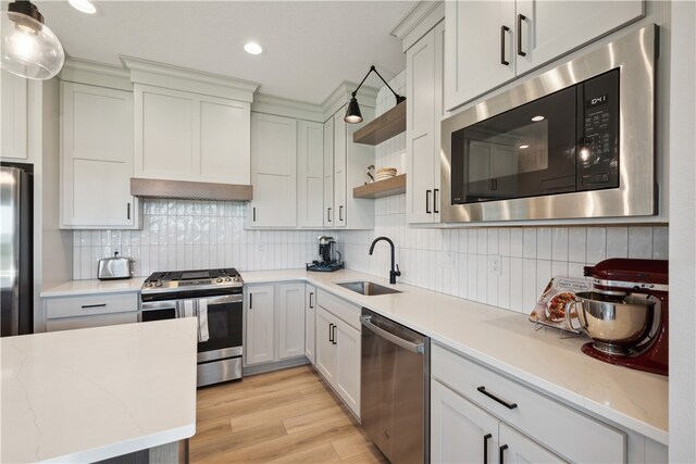 kitchen featuring hanging light fixtures, white cabinetry, appliances with stainless steel finishes, and sink