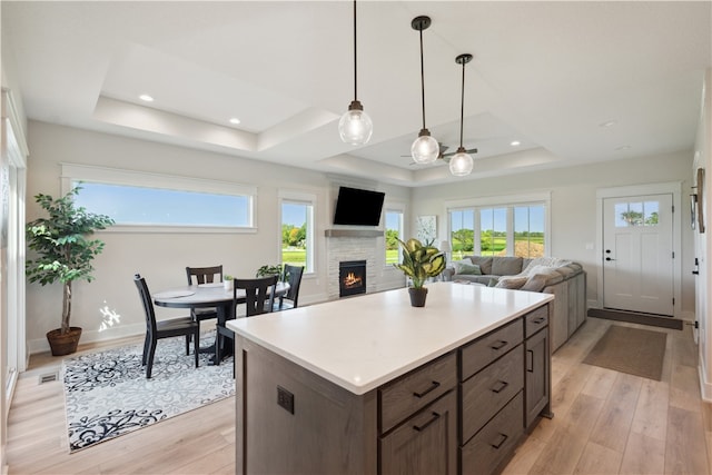 kitchen with dark brown cabinets, a tray ceiling, decorative light fixtures, and light hardwood / wood-style flooring