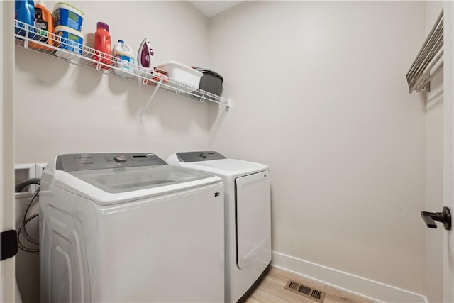 washroom with washer and dryer and light wood-type flooring