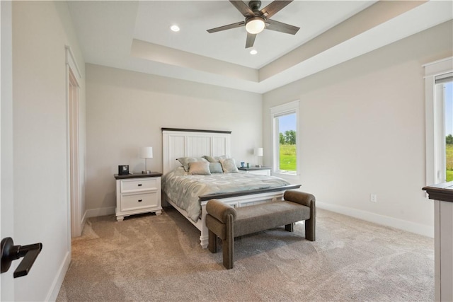 carpeted bedroom featuring a tray ceiling and ceiling fan