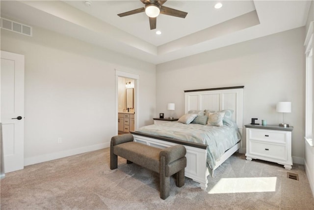 carpeted bedroom with connected bathroom, a raised ceiling, and ceiling fan