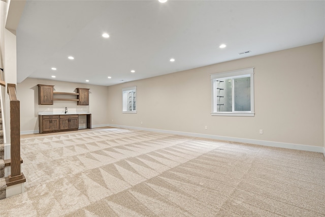 unfurnished living room with sink, a wealth of natural light, and light colored carpet