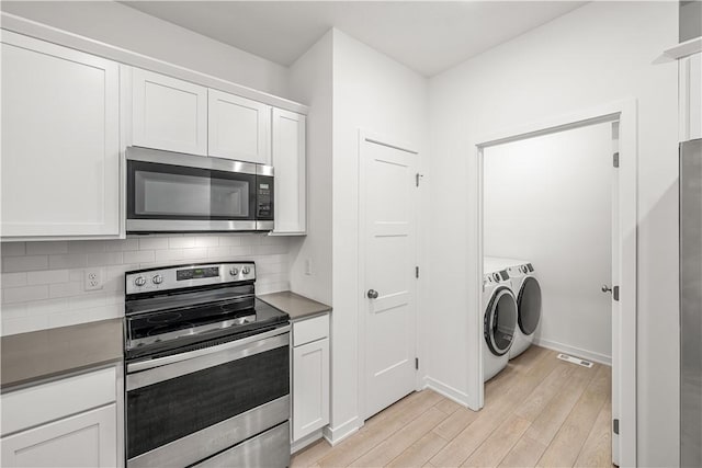 kitchen with white cabinetry, backsplash, stainless steel appliances, washer and clothes dryer, and light hardwood / wood-style flooring