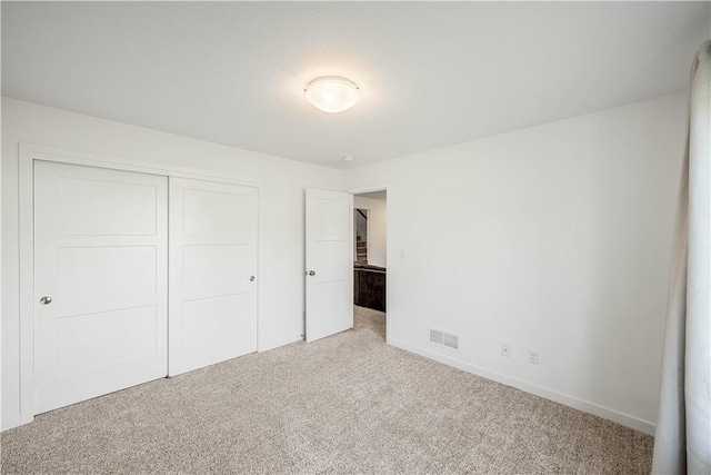 unfurnished bedroom featuring light carpet and a closet