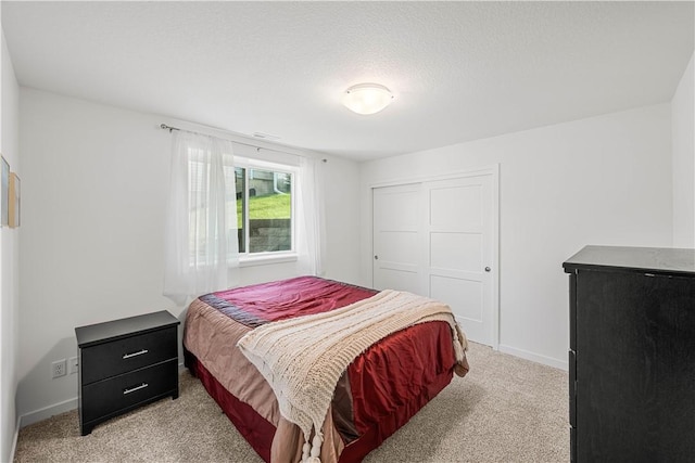 bedroom with light carpet, a textured ceiling, and a closet