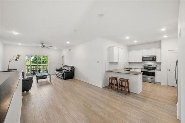 kitchen with sink, a breakfast bar area, appliances with stainless steel finishes, white cabinetry, and kitchen peninsula