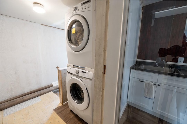 washroom with stacked washer / drying machine and sink