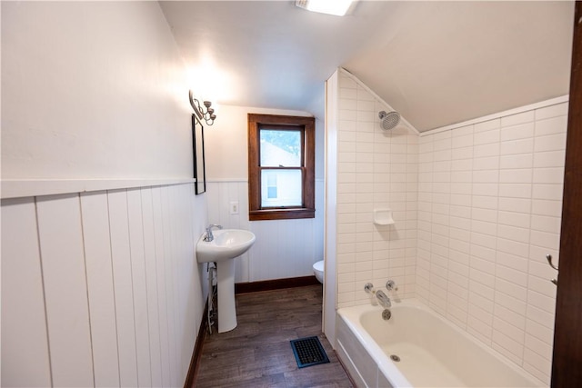 full bathroom featuring toilet, sink, wood-type flooring, vaulted ceiling, and tiled shower / bath combo