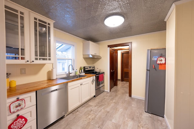 kitchen with white cabinetry, appliances with stainless steel finishes, butcher block counters, and sink