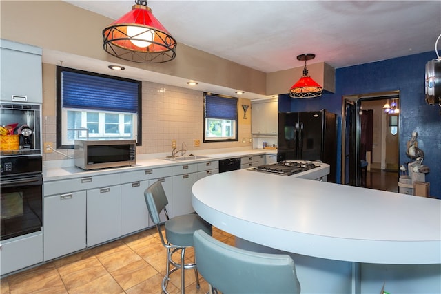 kitchen with black appliances, hanging light fixtures, decorative backsplash, sink, and light tile patterned floors